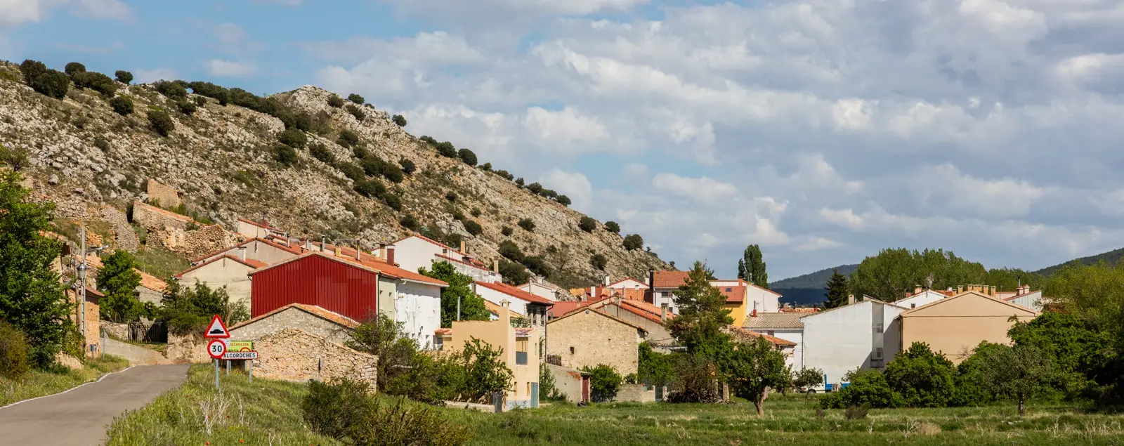 Panoramic view of Alcoroches with village houses and the entrance sign.