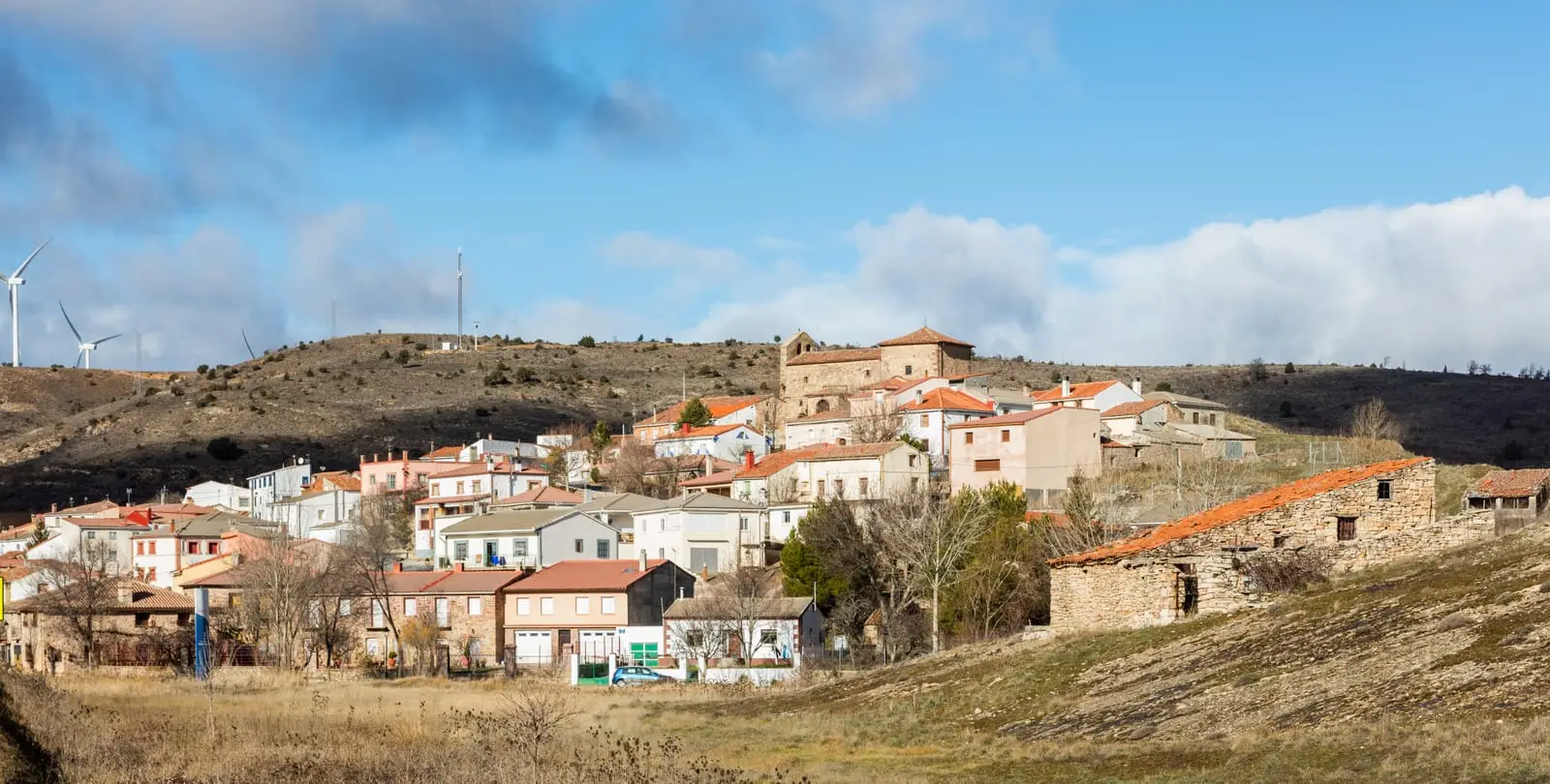 Panoramic view of Anquela del Ducado with the church and houses at the foot of the hillside.