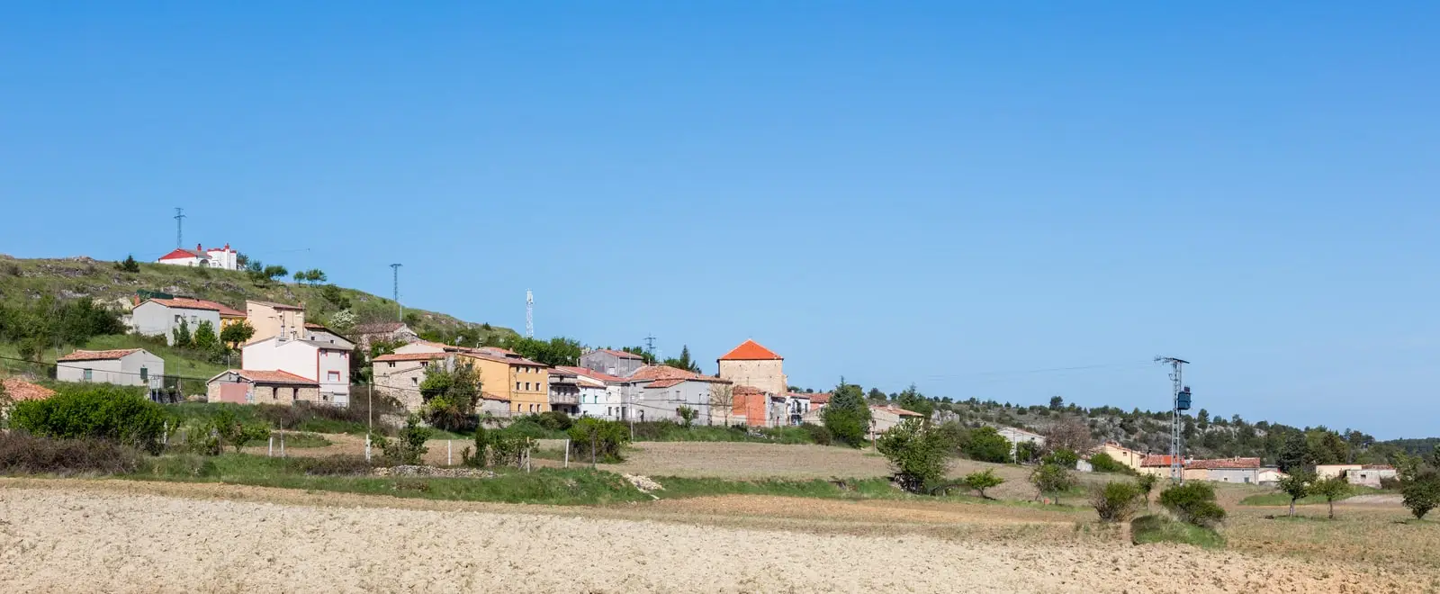 Panoramic view of Armallones with houses, the church and tower beside the hillside.