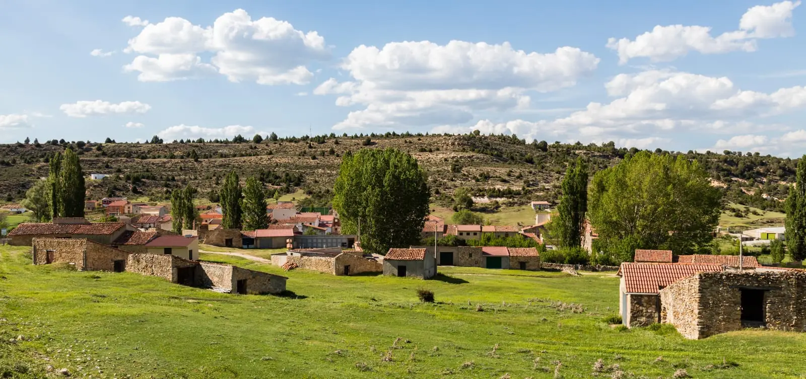 Panoramic view of Baños de Tajo beside the hillside and meadows surrounding its houses.