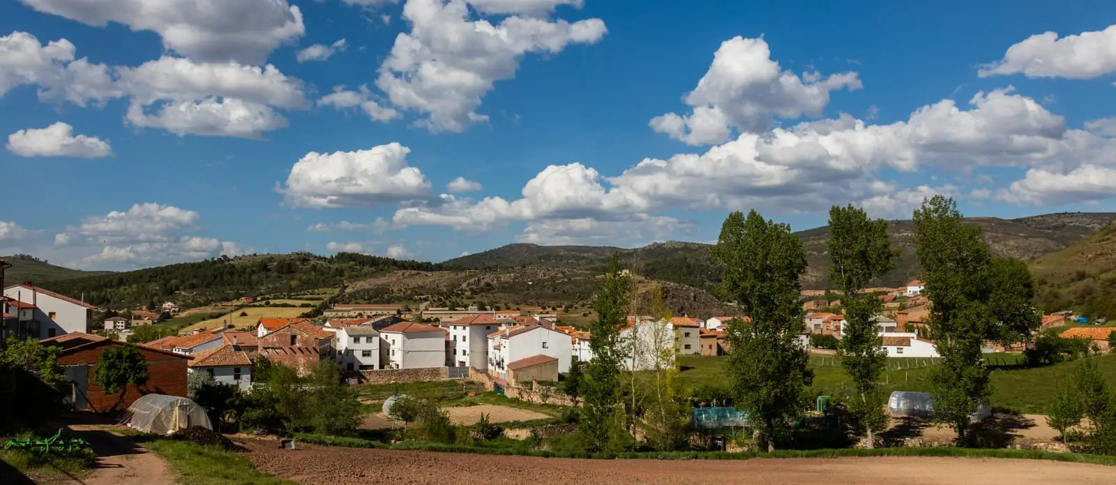 Panorámica del casco urbano de Checa, con casas tradicionales rodeadas de prados y lomas.
