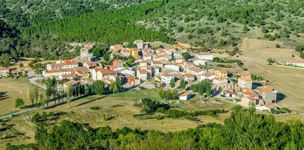Elevated view of Canales del Ducado, with clustered houses and trees on the hillside.