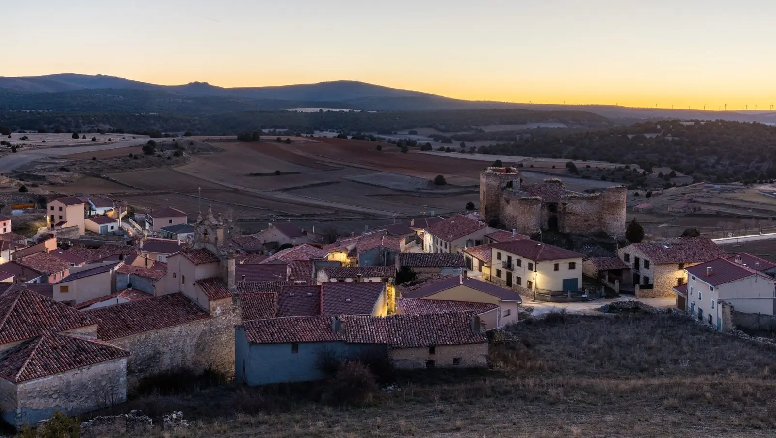 Panoramic view of Establés at dusk, with the castle above the village houses.