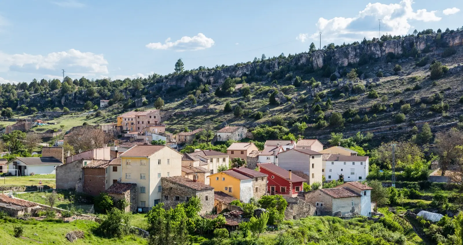 Panoramic view of Fuembellida, Guadalajara, in a valley below limestone cliffs.