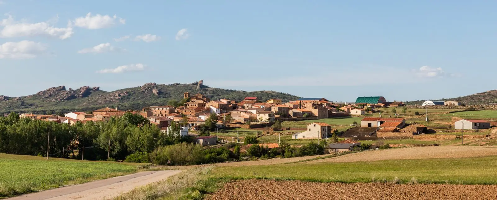 Panoramic view of Hombrados, with village houses and rock outcrops behind.