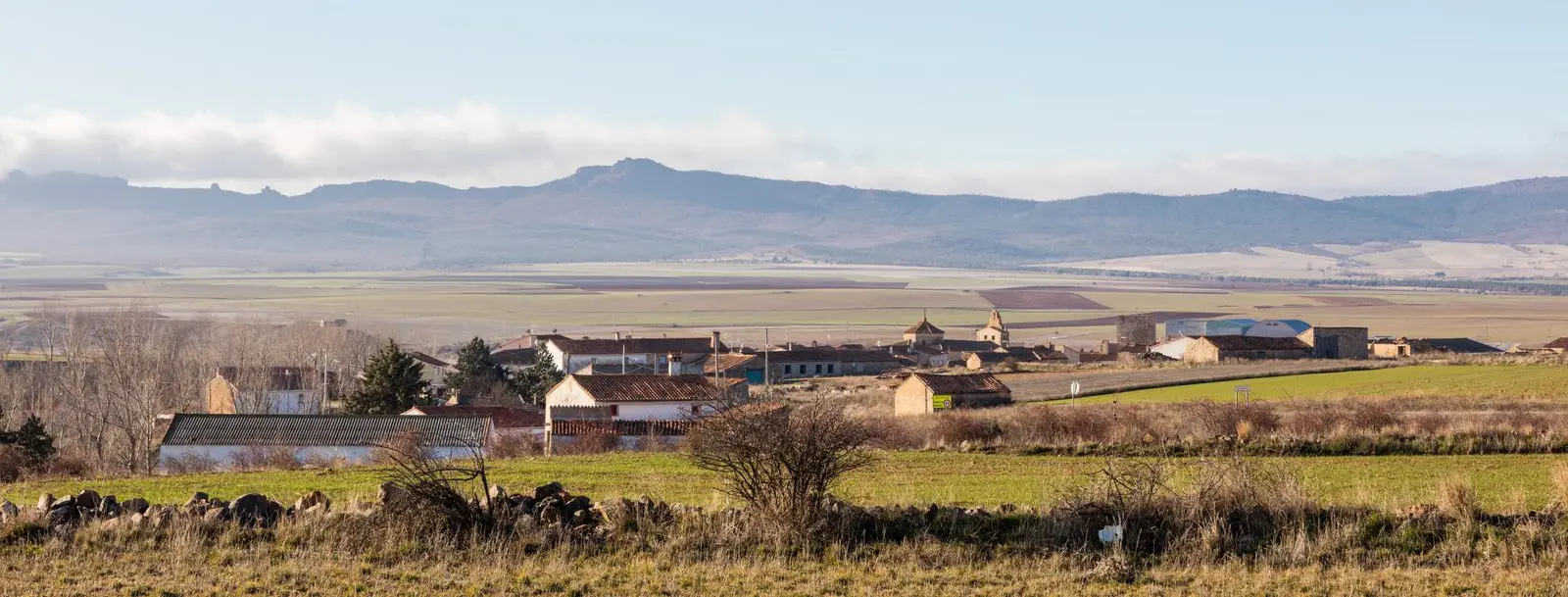 Panoramic view of La Yunta among fields, with the church tower visible.