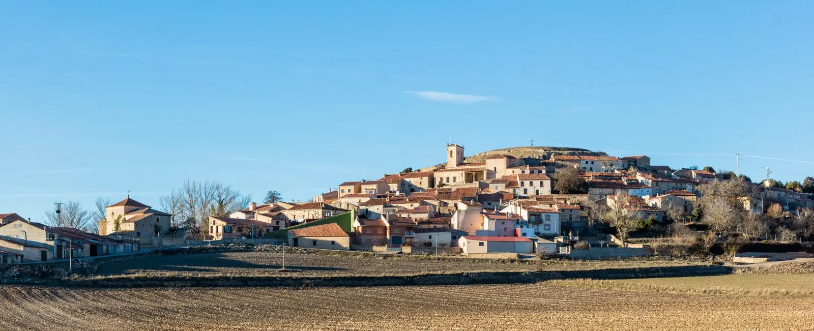 Panoramic view of Labros, with stone houses clustered on the hillside and fields in front.