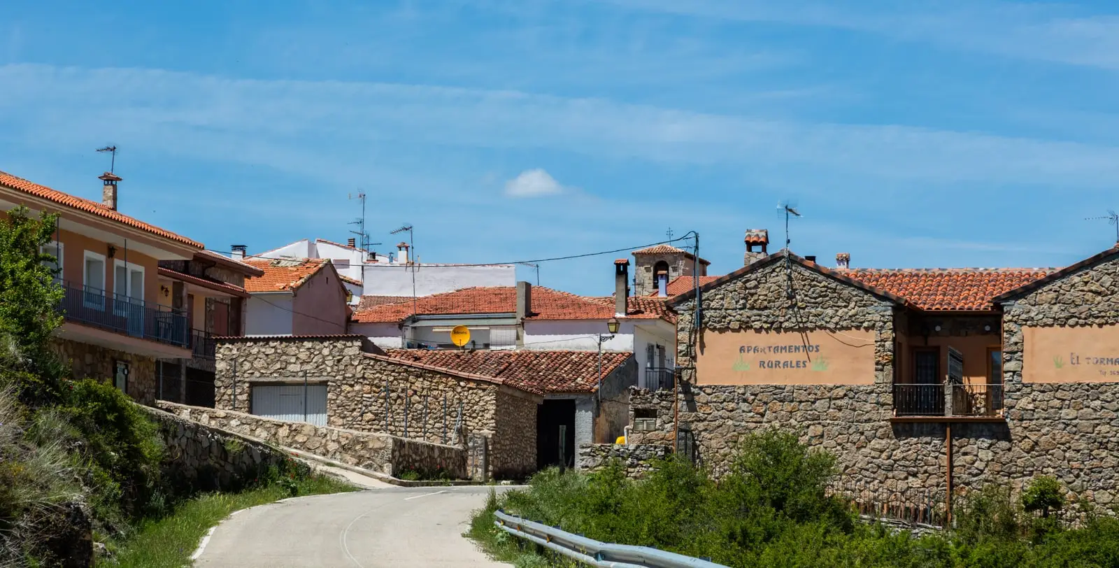 Street between stone houses and reddish roofs in Masegosa, Cuenca.