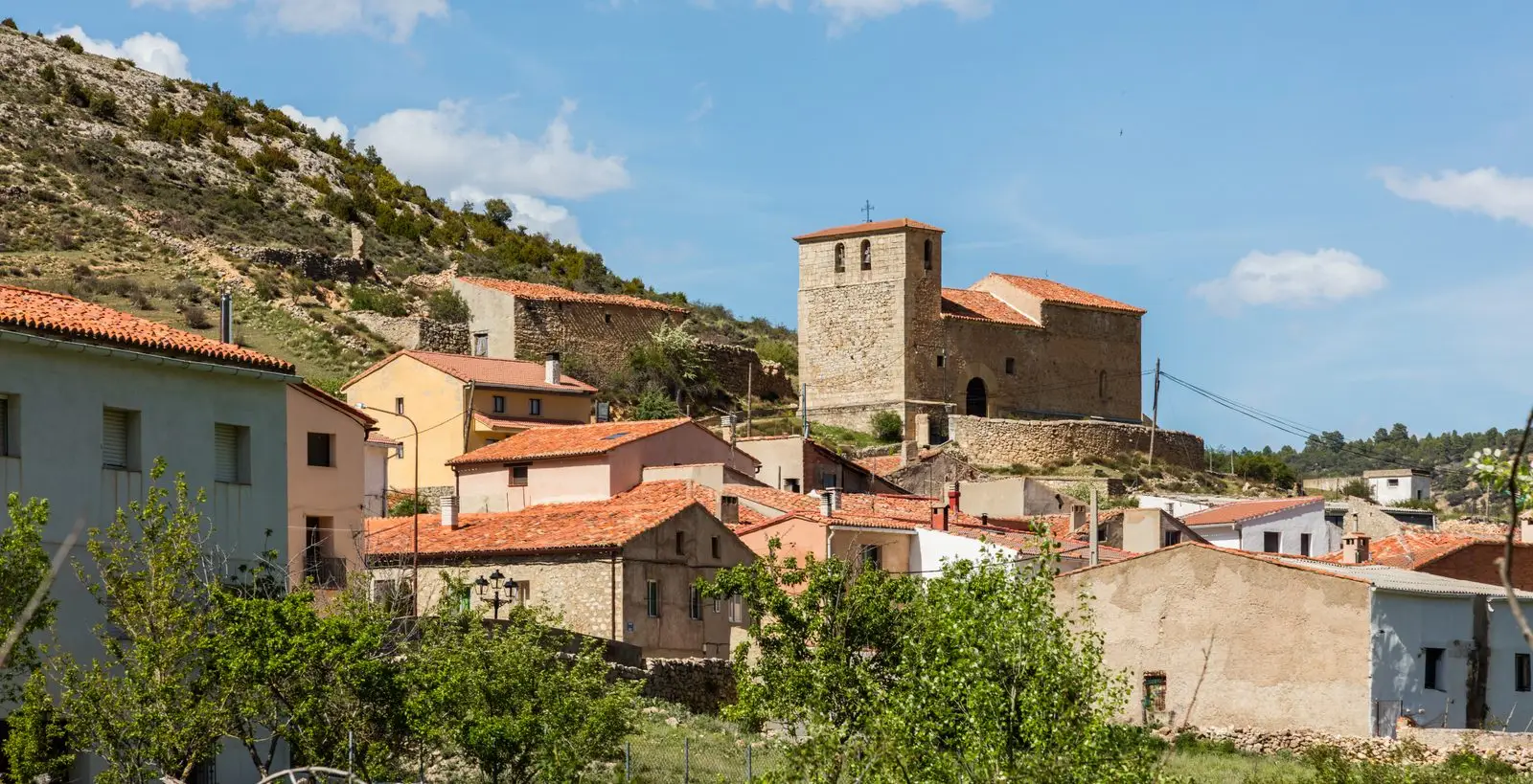 Megina with its stone church and village houses among rocky slopes.