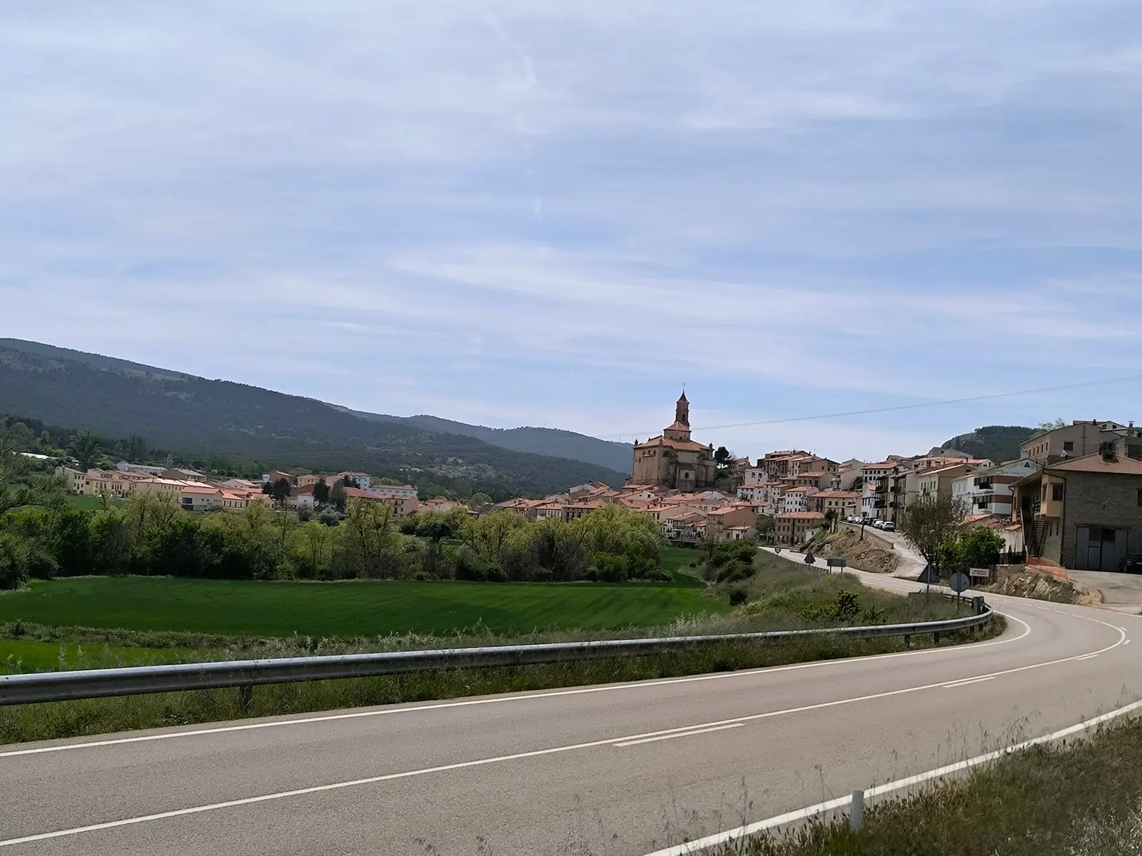 Vista de Orihuela del Tremedal desde la carretera, con la iglesia y las casas del núcleo al pie de la sierra.