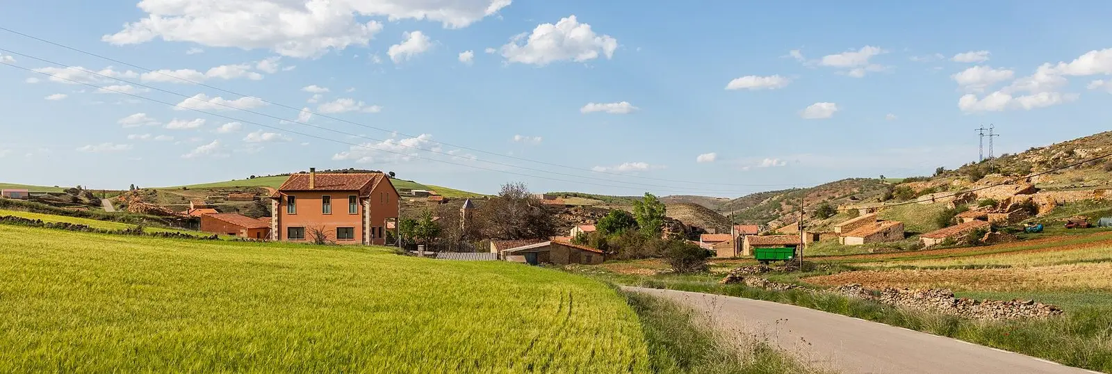 Panoramic view of Tordellego with village houses among fields and hillsides.