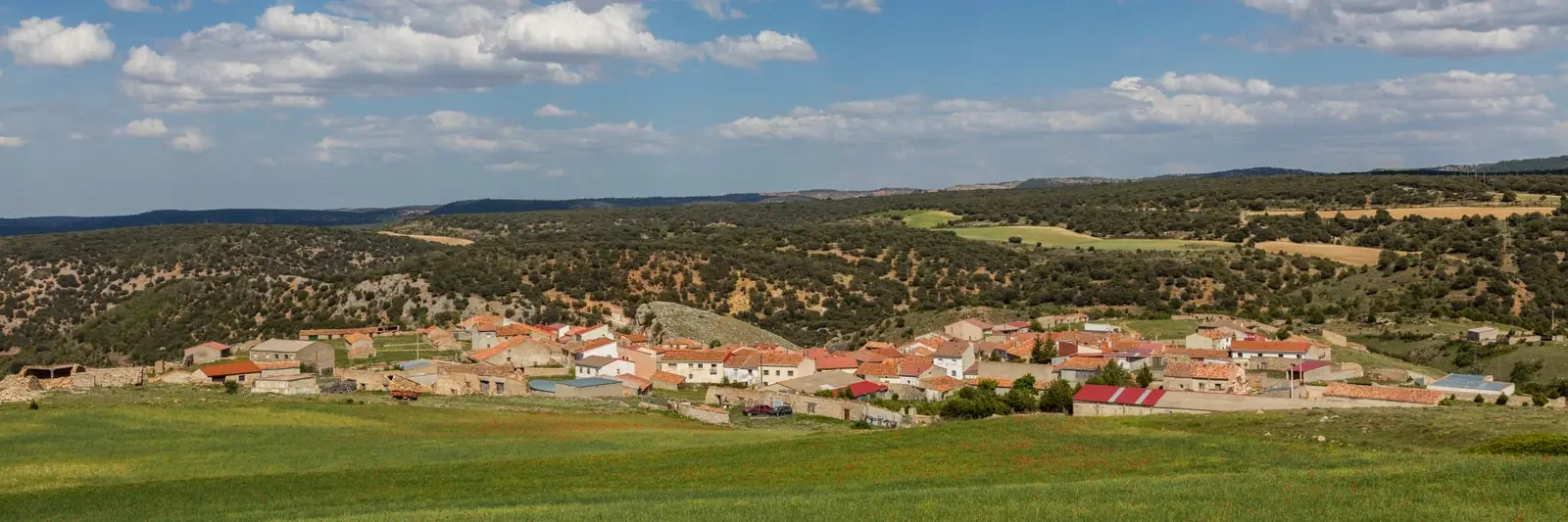 Panoramic view of Traíd with houses below scrub-covered hills.