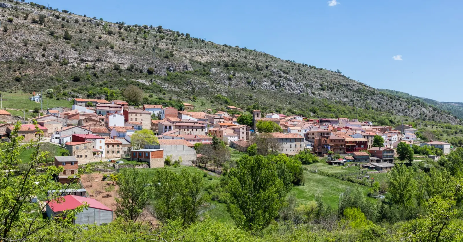 Panoramic view of Valsalobre with houses clustered beneath a rocky hillside.