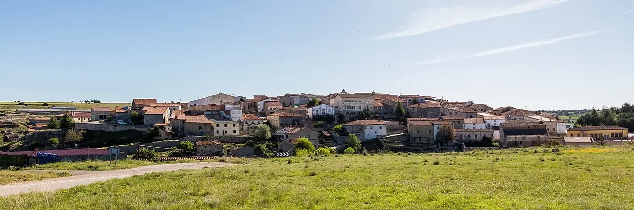 Panoramic view of Villanueva de Alcorón’s houses surrounded by fields and trees.
